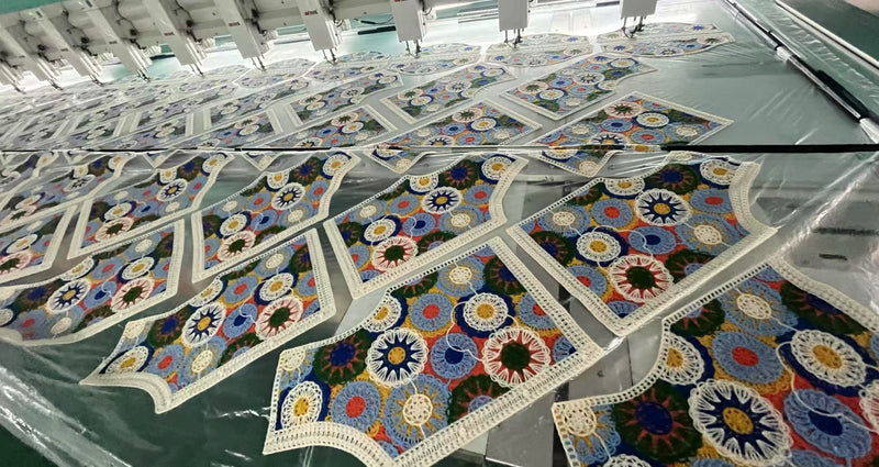 Rows of colorful granny square crochet vest fabric panels laid on multi-head embroidery machine at BENTA factory, OEM knitwear cut pieces in production.
