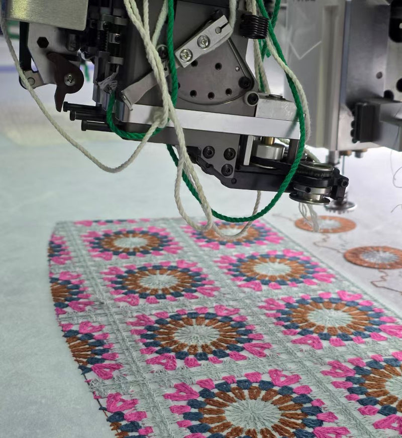 BENTA factory close-up shot of automatic embroidery machine head stitching colorful geometric crochet pattern fabric panels, textile OEM workshop production.