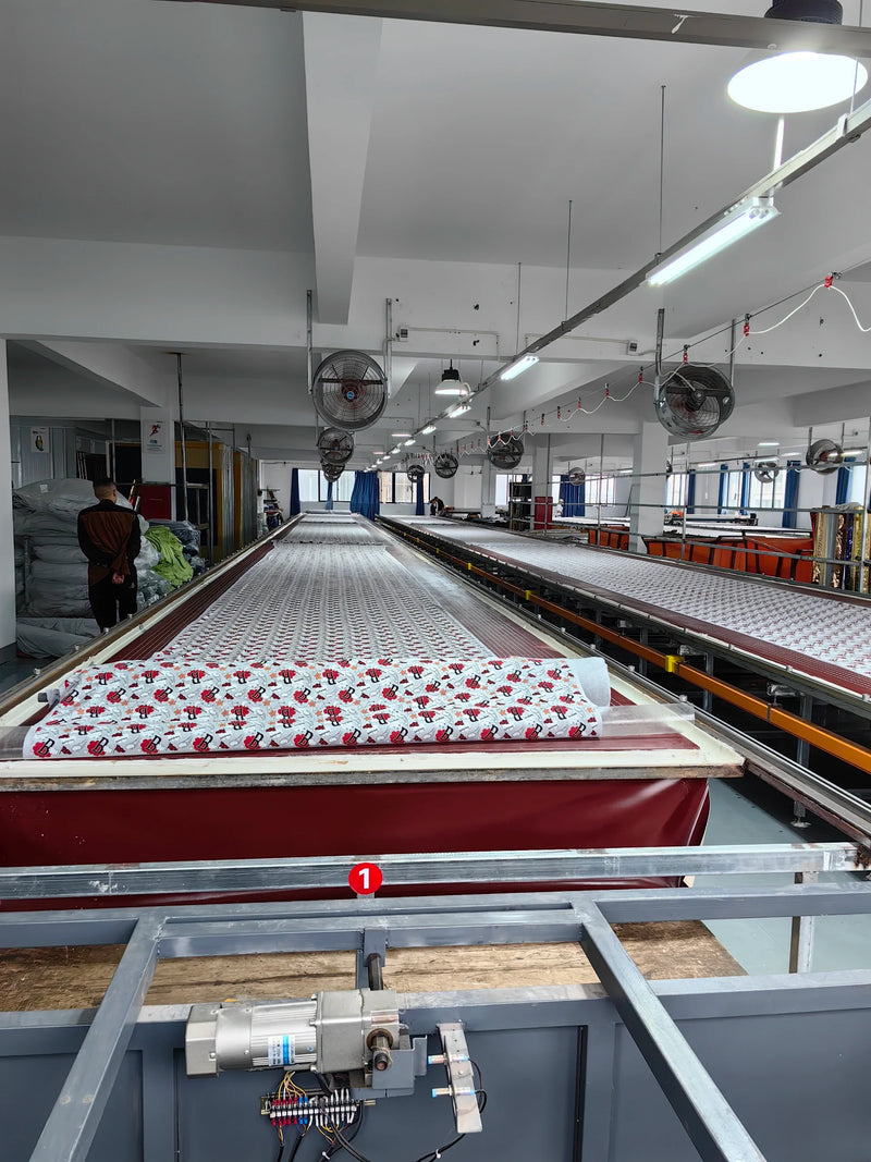 Wide overview of BENTA production workshop, long conveyor tables laid with floral crochet fabric for OEM knitwear and textile manufacturing.